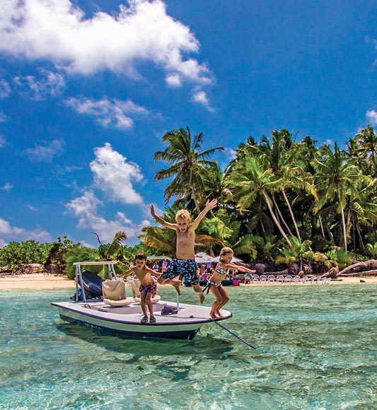 Children jumping out of boat on Alphonse Island in the Seychelles