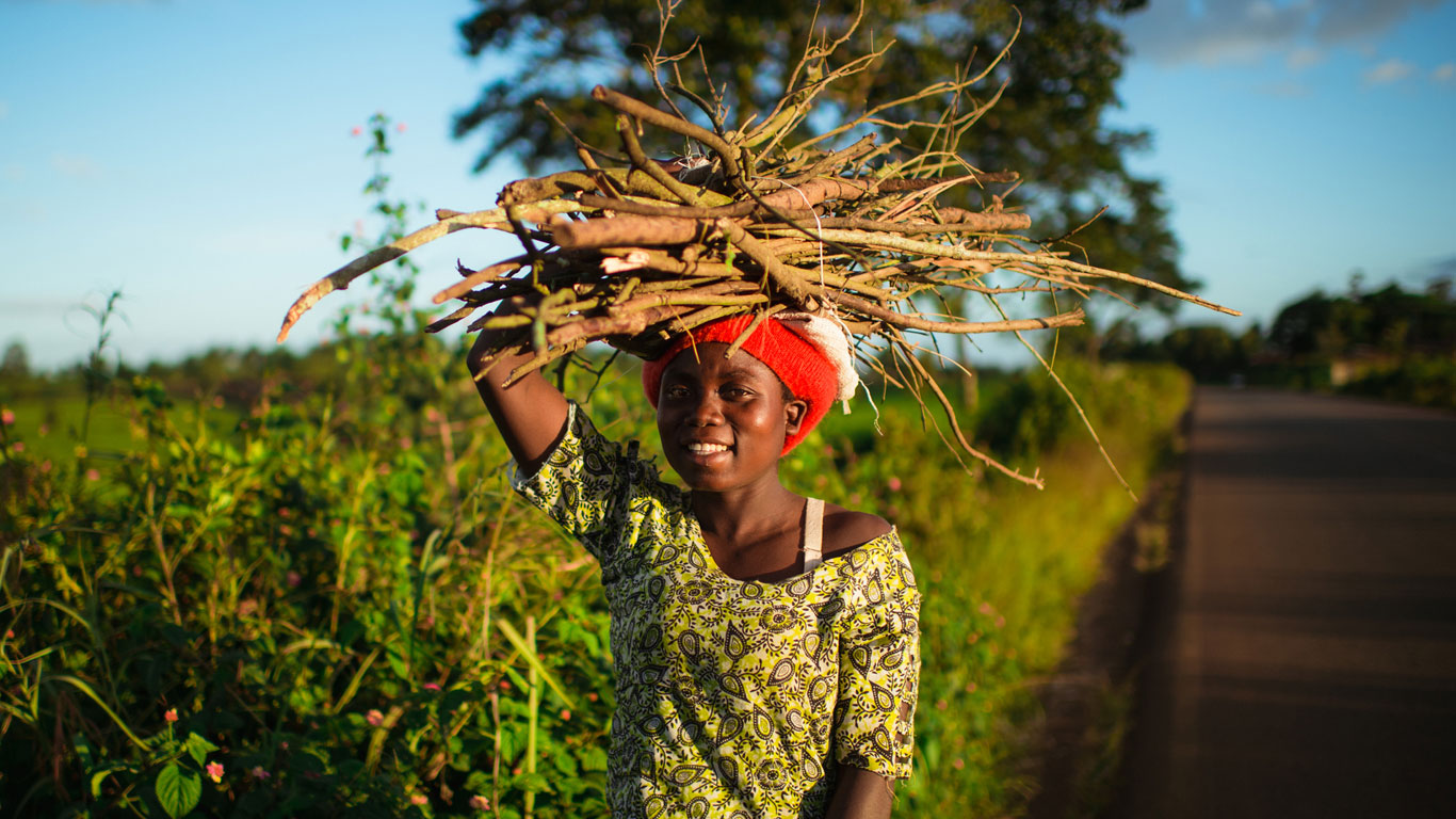 African woman in Malawi carrying pile of sticks