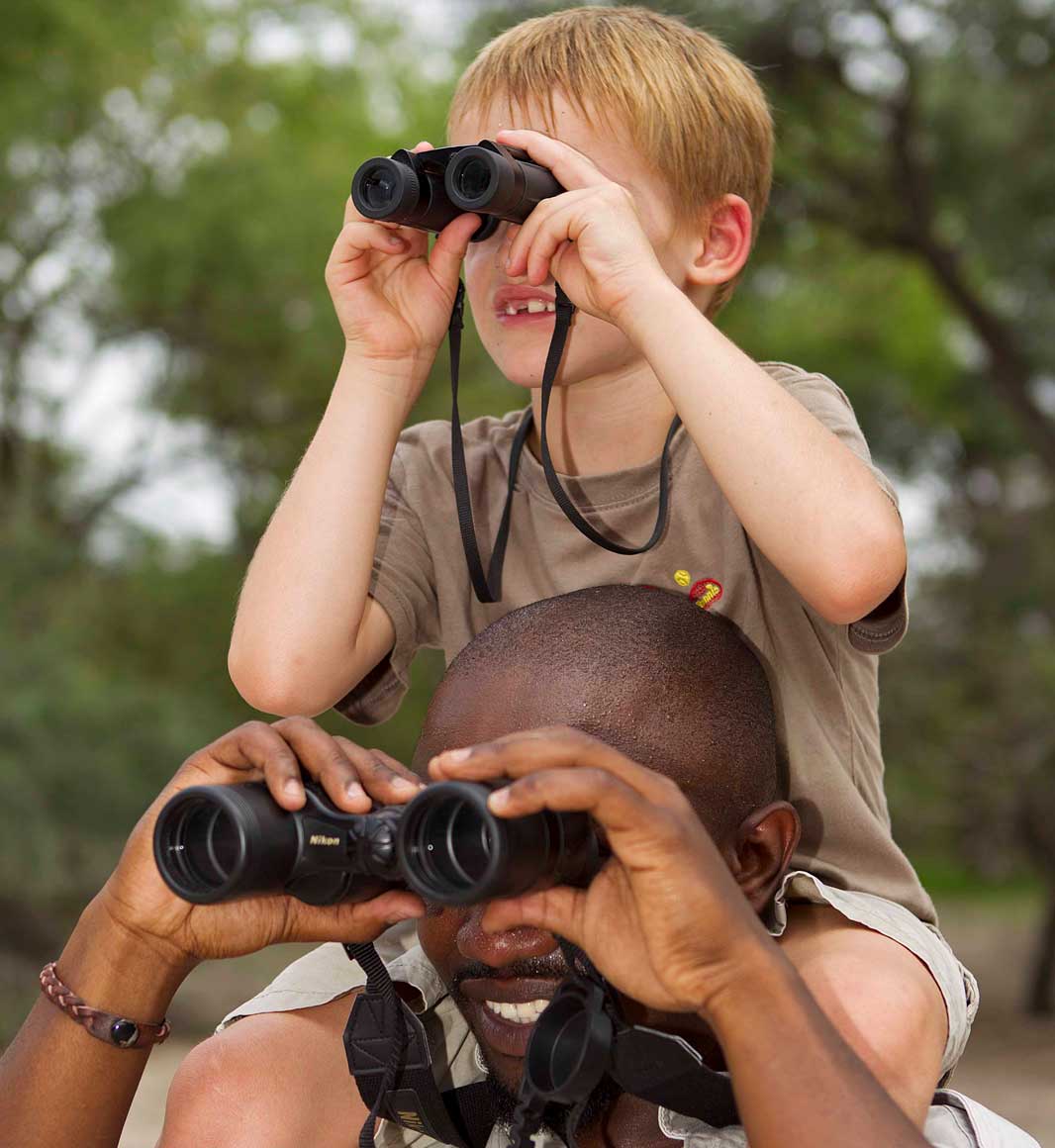 Child with binoculars on family safari in Botswana