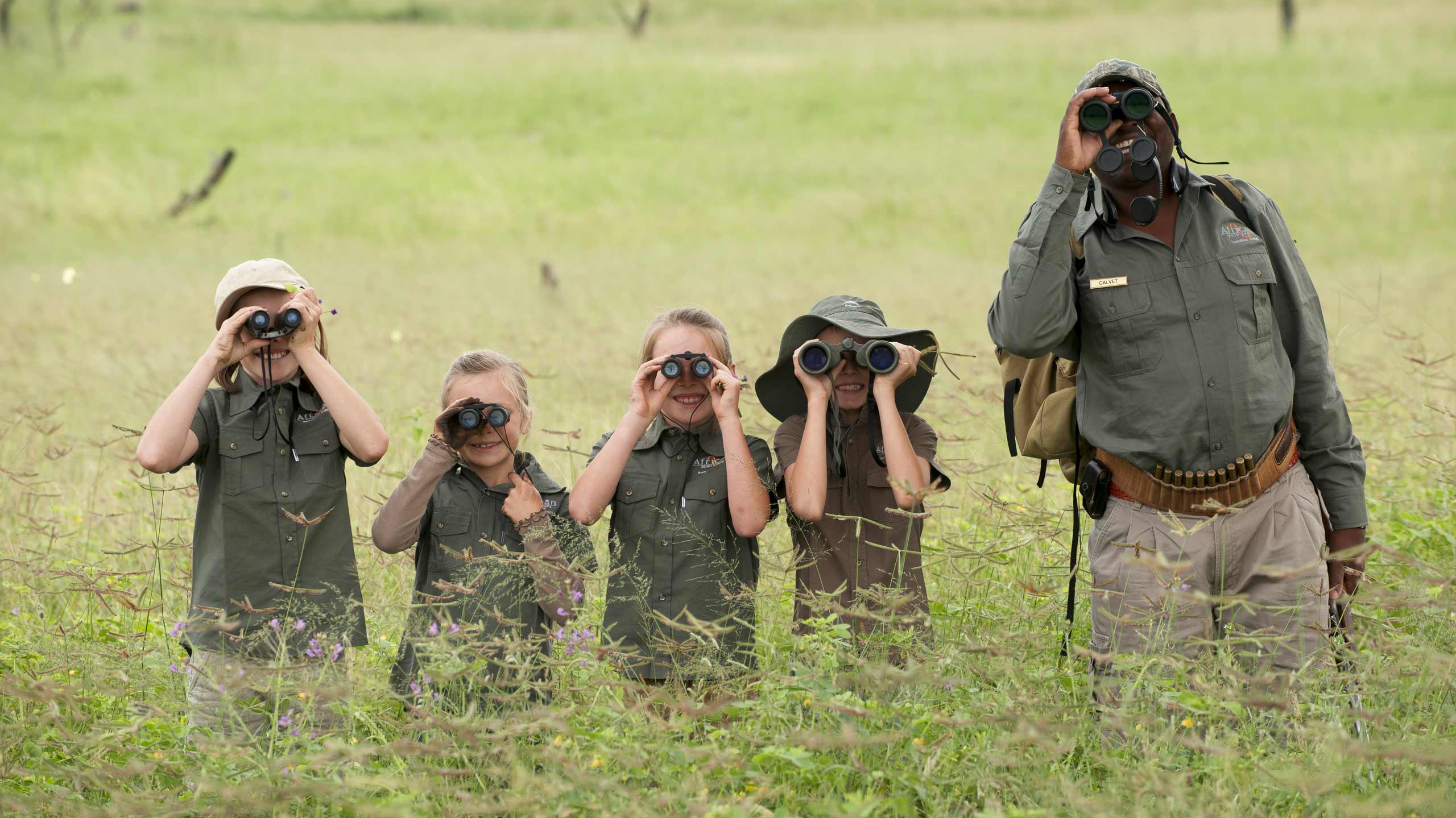 Children using binoculars on family safari in Africa