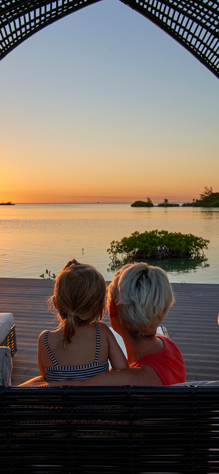 Mother and daughter watching sunset on family holiday