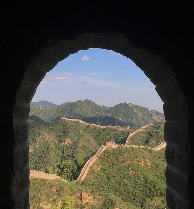 great wall of china seen through an archway of a defensive station