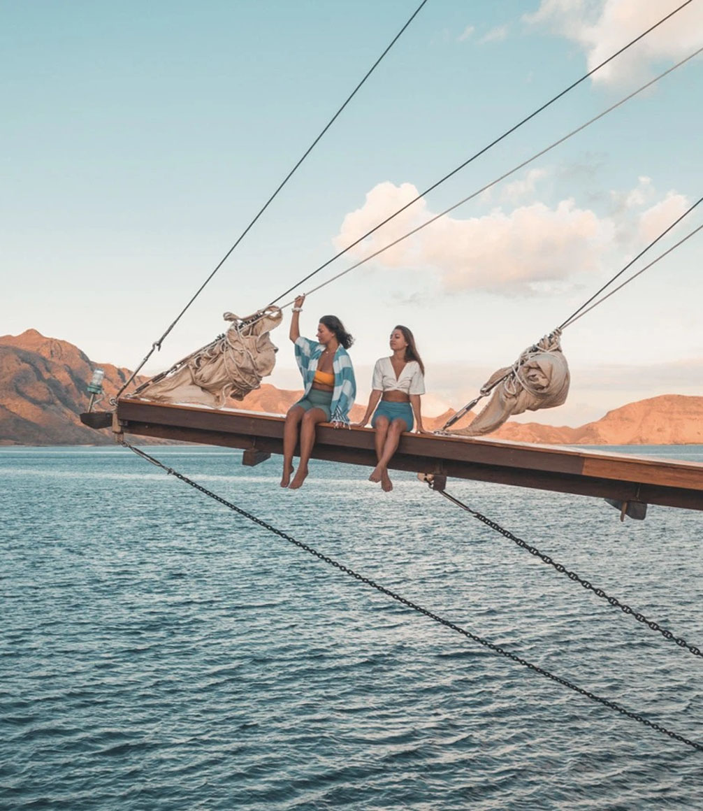 two women sat on bow of sailing ship dewata in indonesia