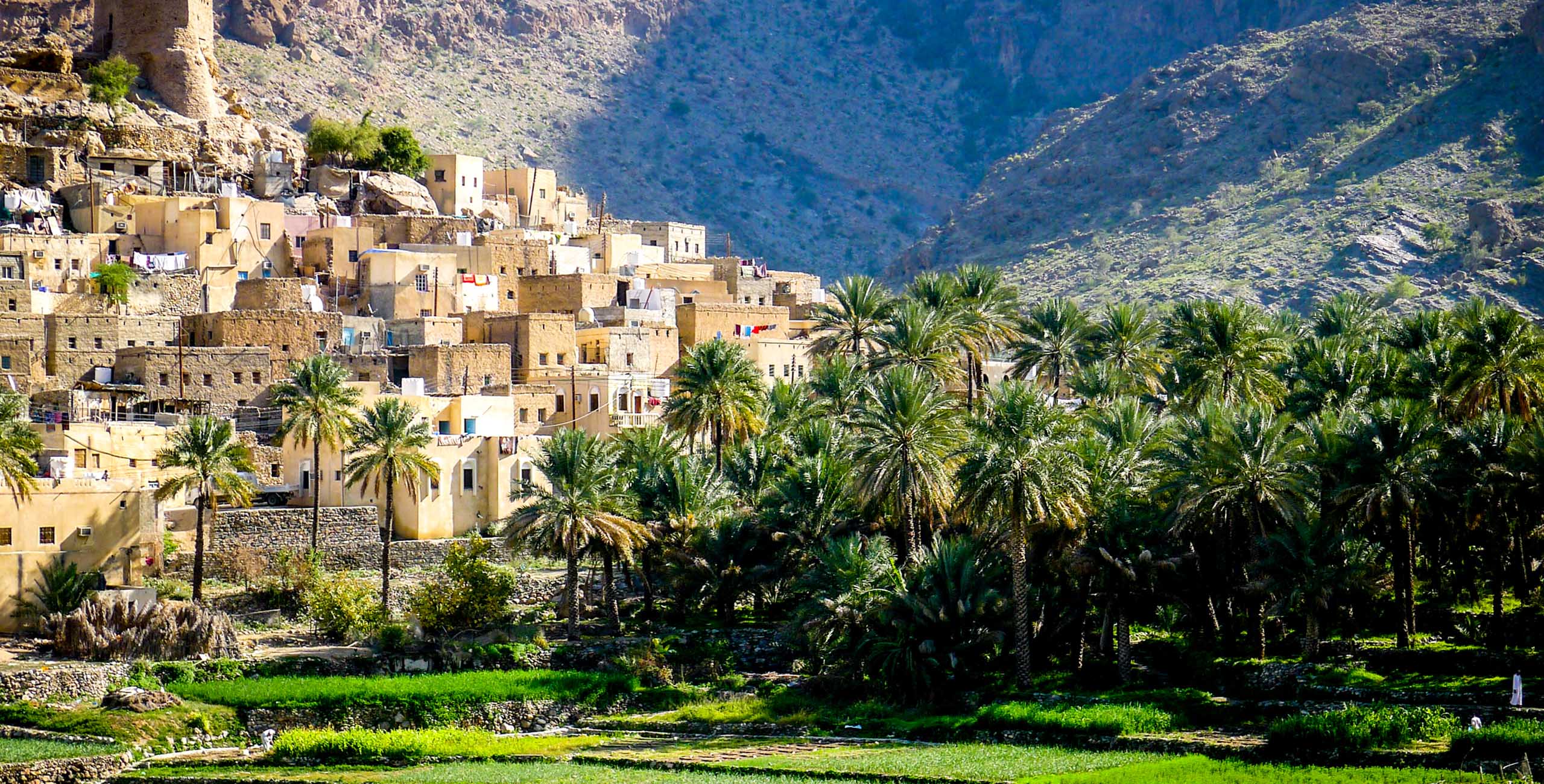 The beautiful mountain village of Balad Sayt sits in front of green fields in Wadi Bani Awf, Oman