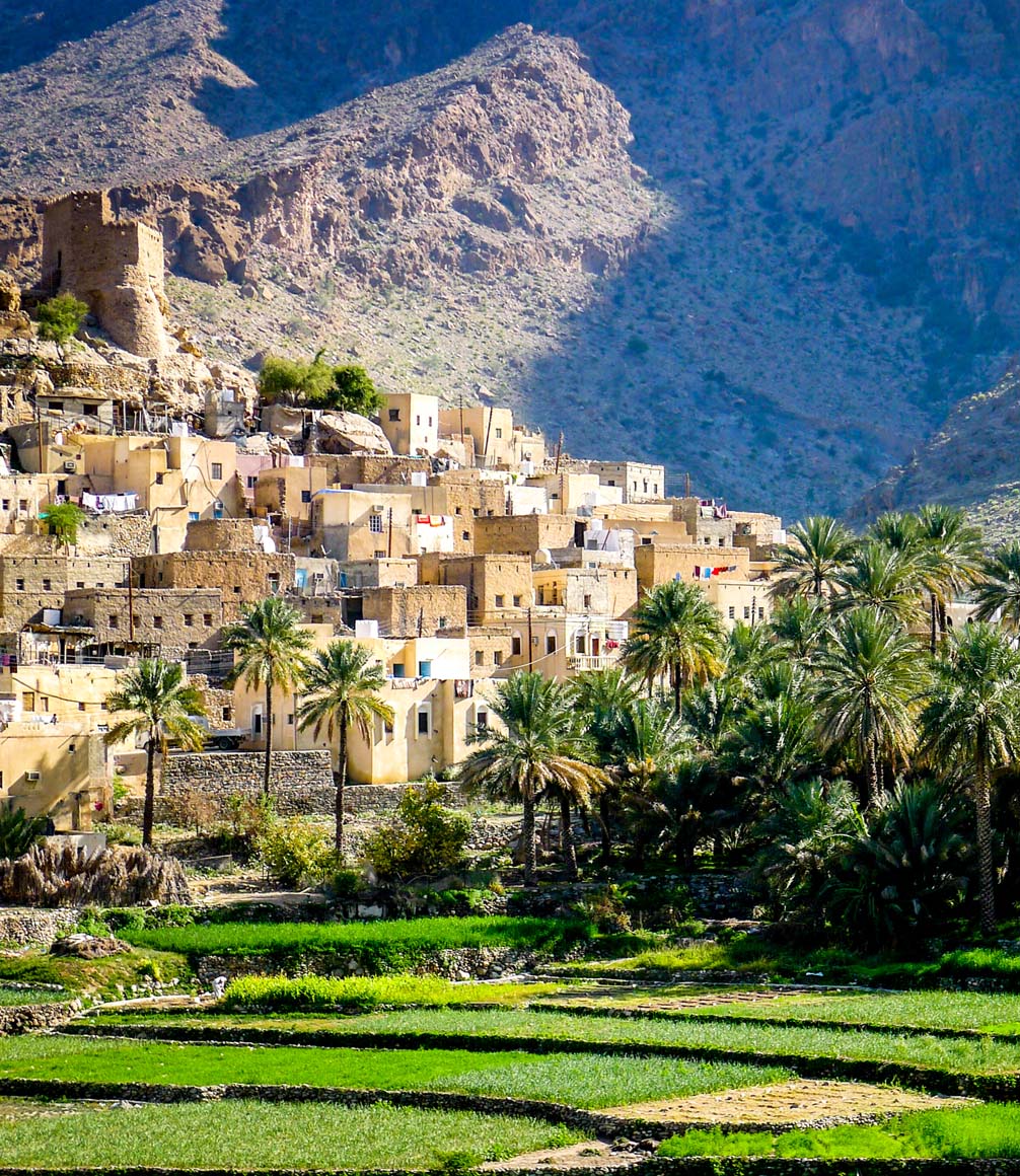 The beautiful mountain village of Balad Sayt sits in front of green fields in Wadi Bani Awf, Oman