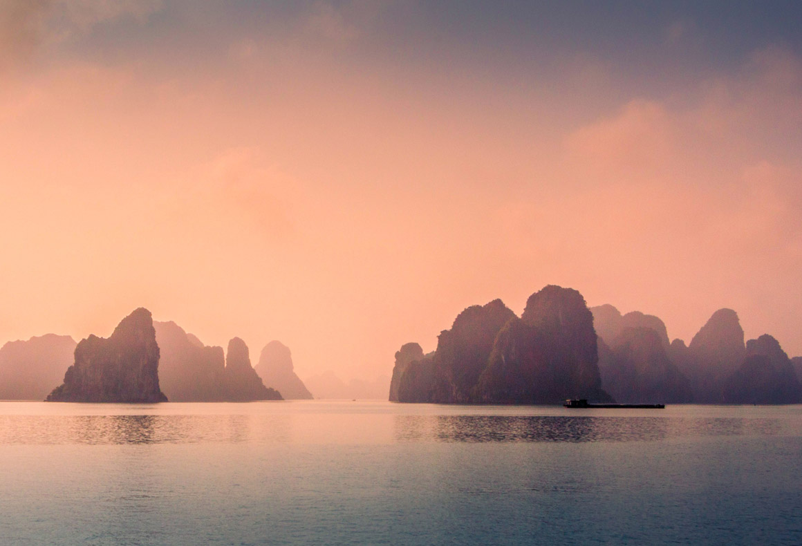 Aerial view of sunset and dawn near rock island, Halong Bay, Vietnam, Southeast Asia. UNESCO World Heritage Site. Junk boat cruise to Ha Long Bay. Popular landmark of Vietnam