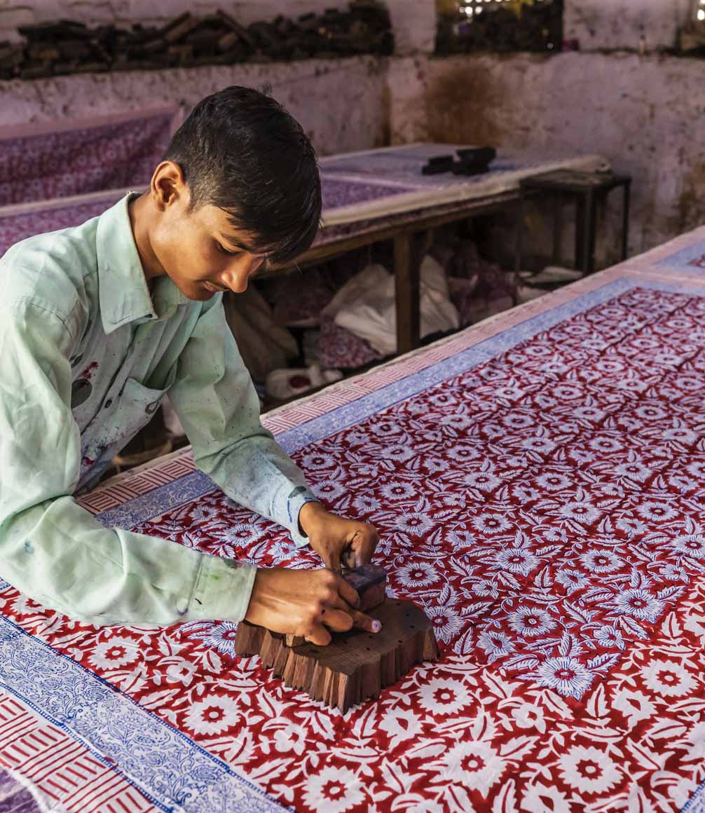Young man working in block printing factory in Jaipur, India, Jaipur is famous for a screen and block printing. Block printing is the process of printing patterns by means of engraved wooden blocks.