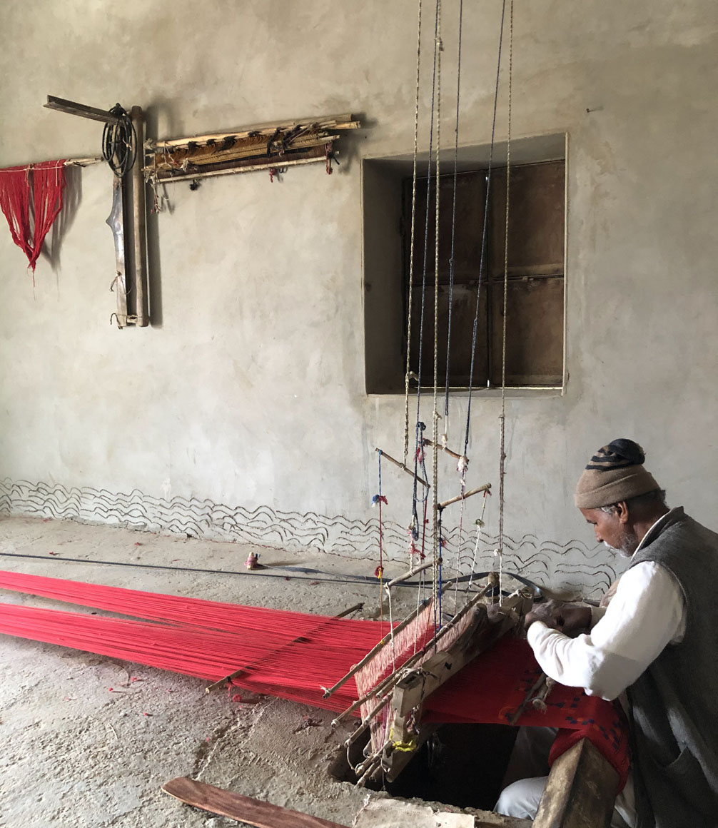 local man using traditional weaving craft in thar desert, india