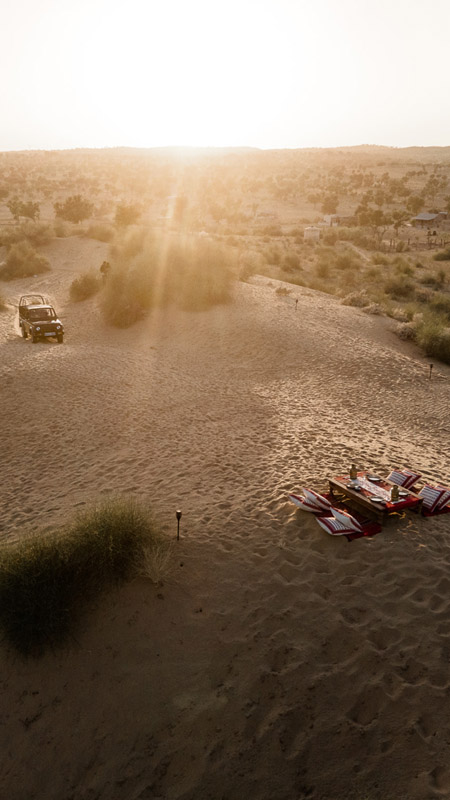sunset in the thar desert with jeep approaching a picnic table
