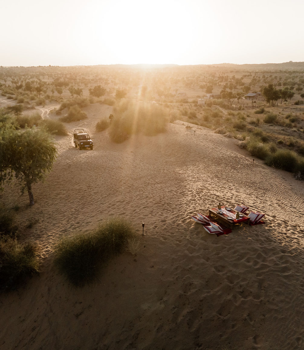sunset in the thar desert with jeep approaching a picnic table