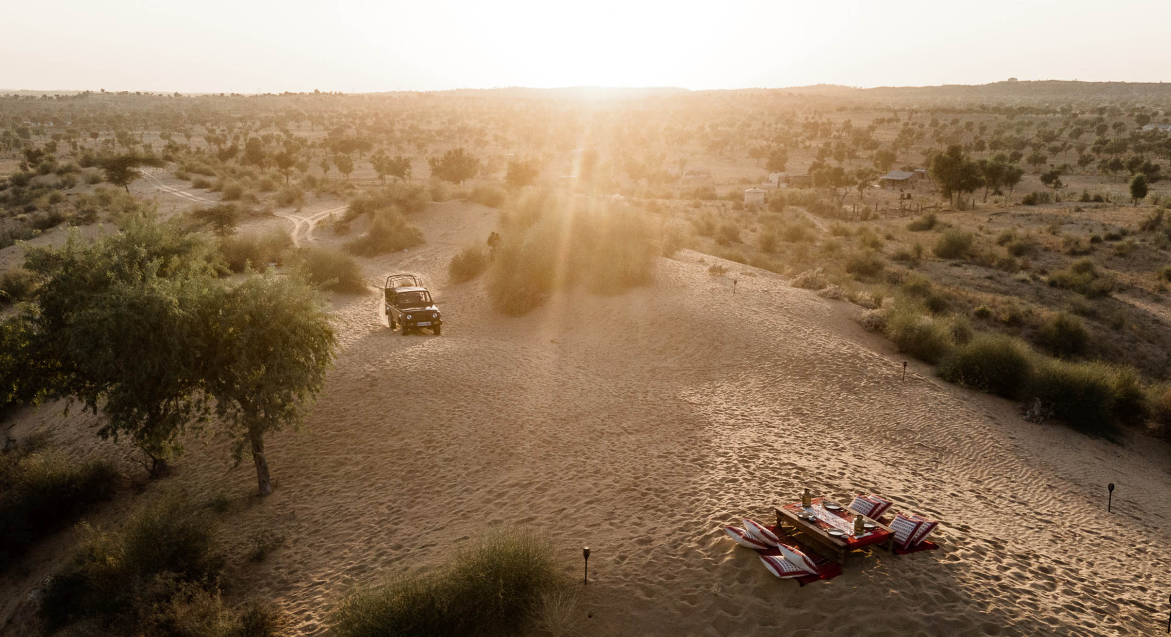 sunset in the thar desert with jeep approaching a picnic table