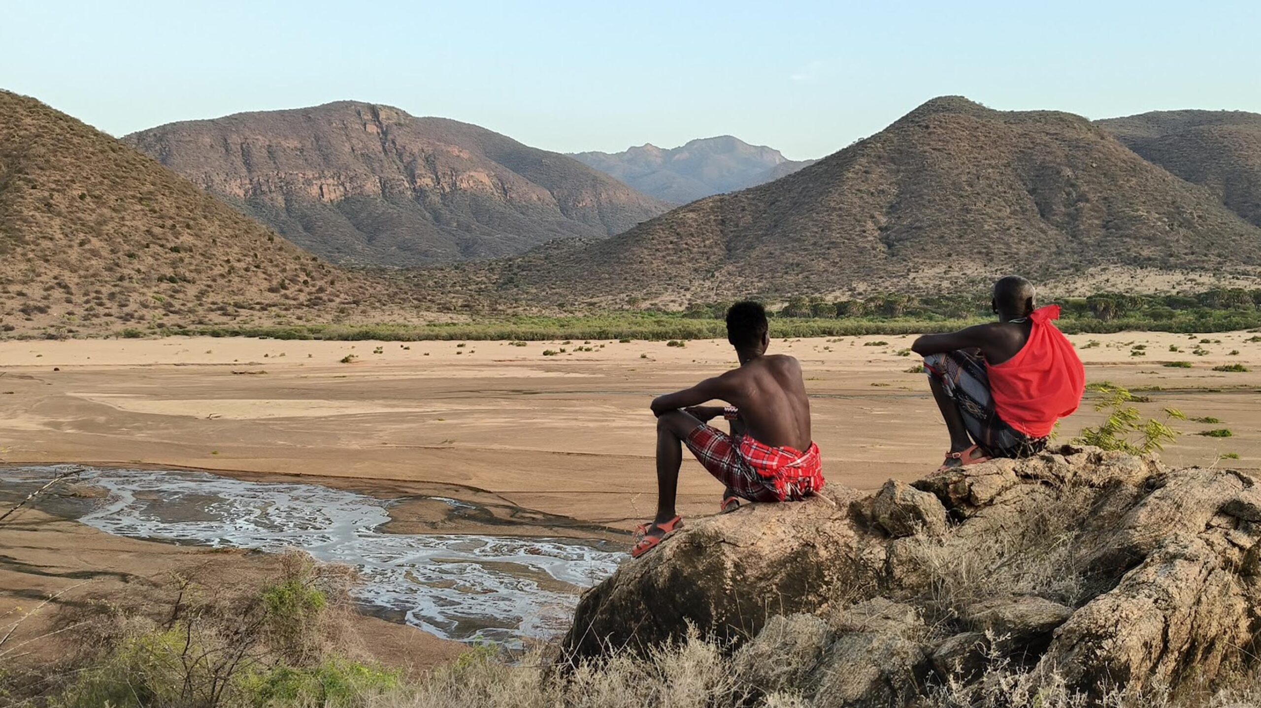 samburu people sat on rocks overlooking the landscape of milgis lugga in kenya