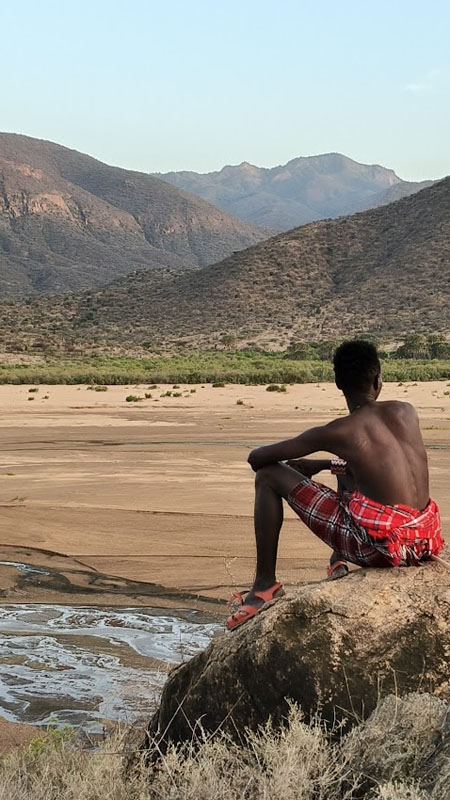 samburu people sat on rocks overlooking the landscape of milgis lugga in kenya