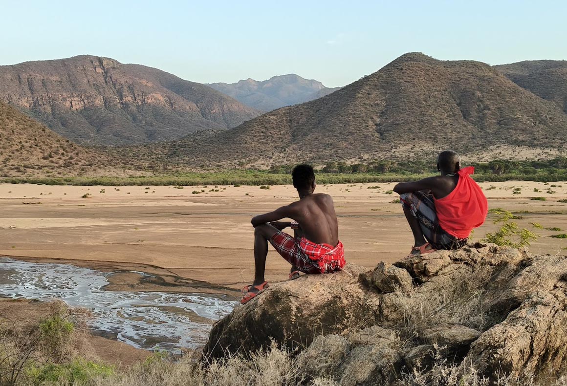 samburu people sat on rocks overlooking the landscape of milgis lugga in kenya