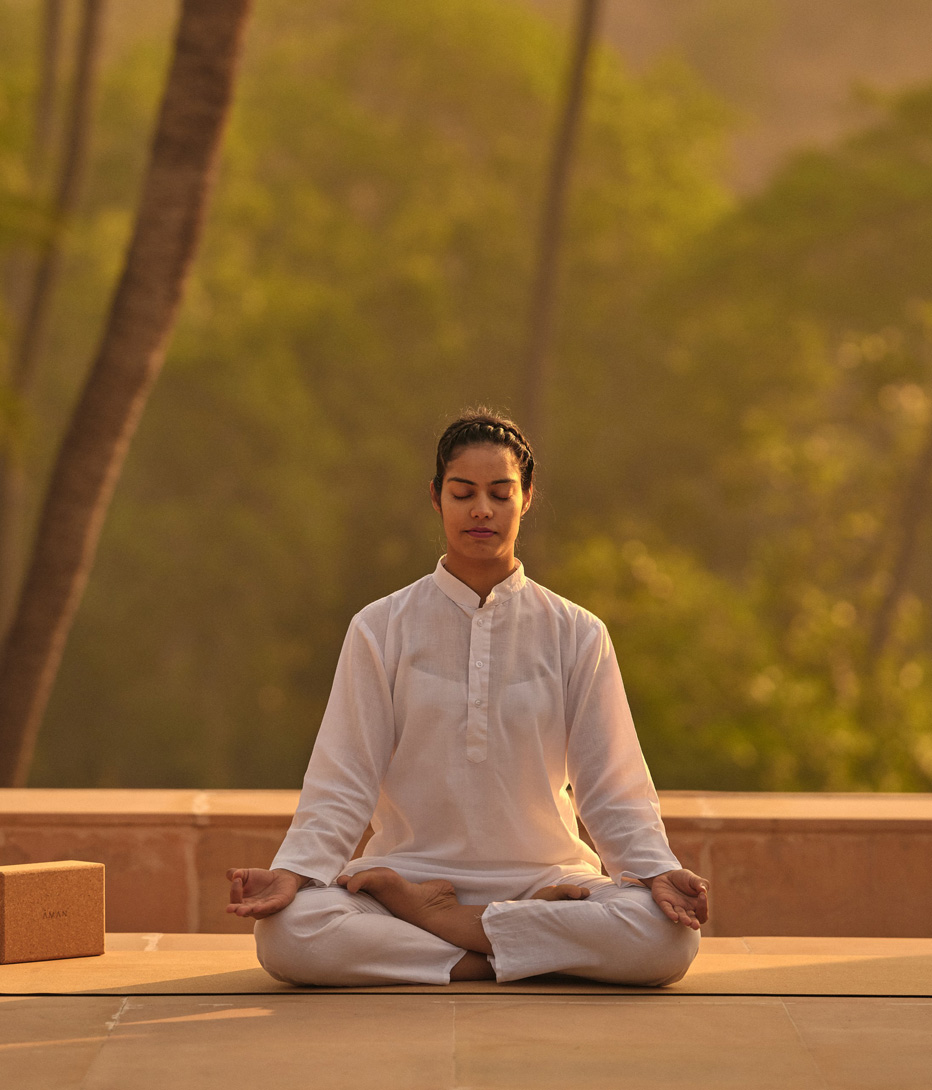 woman meditating in a morning yoga session at amanbagh, india