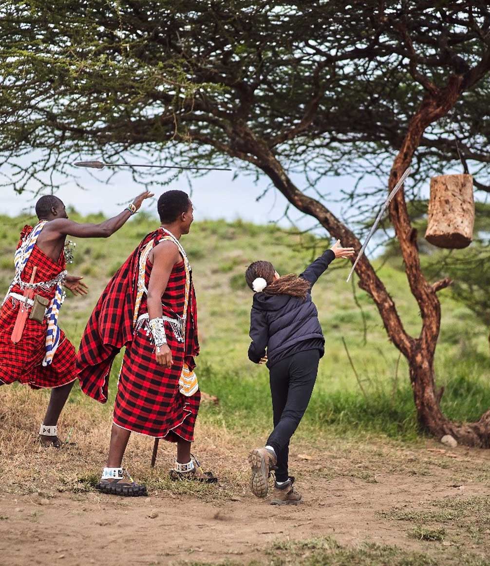 Child learning to throw maasai spears with maasai tribe at amini lodge in northern tanzania on a luxury family safari
