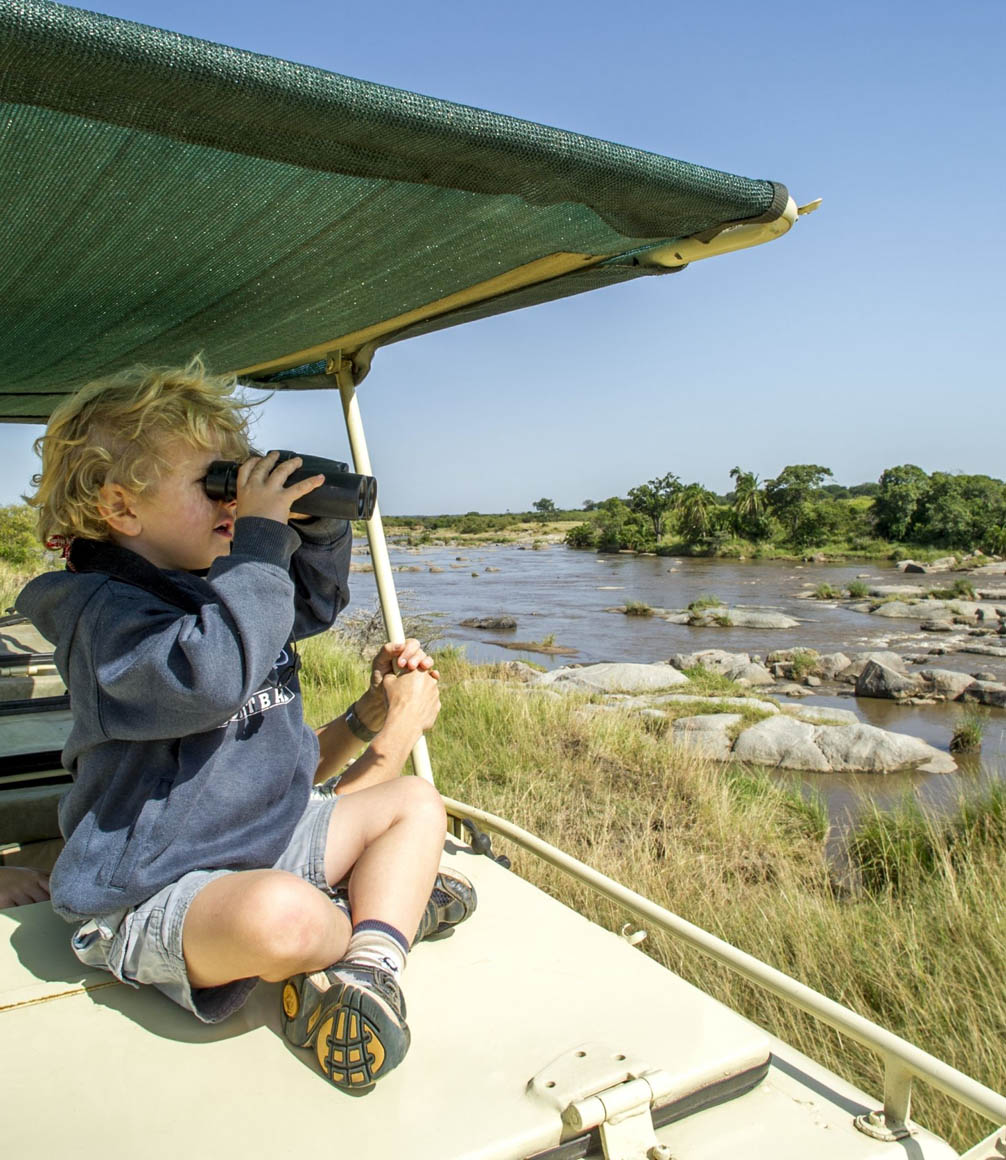 child on game drive with binoculars in Tanzania at Mkombes house