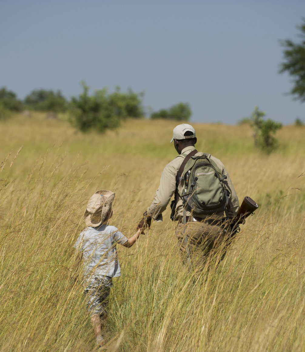 child walking with safari guide at mkombe's house in the serengeti on a family safari
