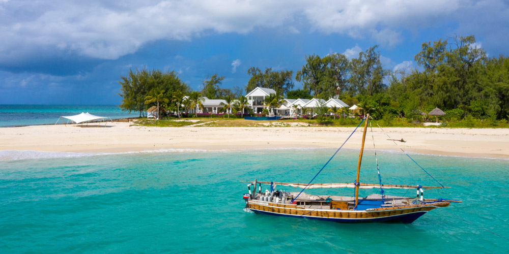 dhow off the shore of Thanda island with the villa on the beach
