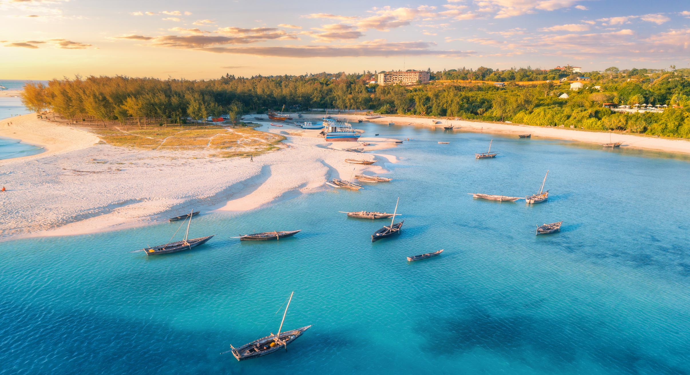 Aerial view of the fishing boats on tropical sea coast with sandy beach at sunset. Zanzibar, Africa