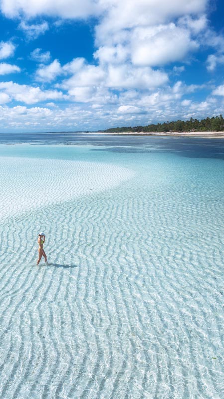 woman on sandbar off beach in zanzibar tanzania