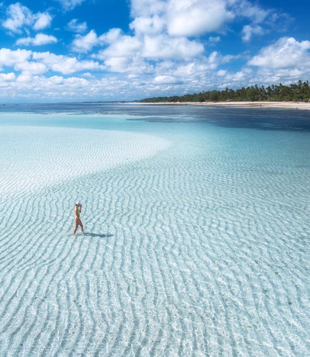 woman on sandbar off beach in zanzibar tanzania