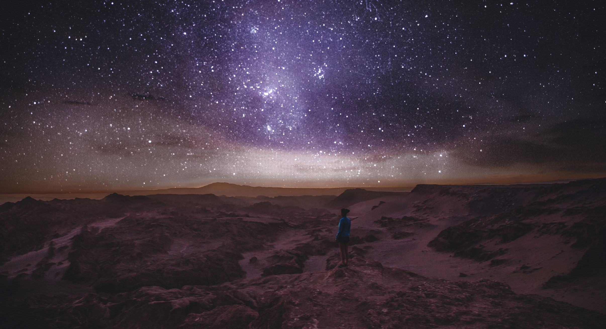 Woman enjoying stargazing under the night sky with million of stars and Milky Way at beautiful canyon on Atacama Desert in Chile
