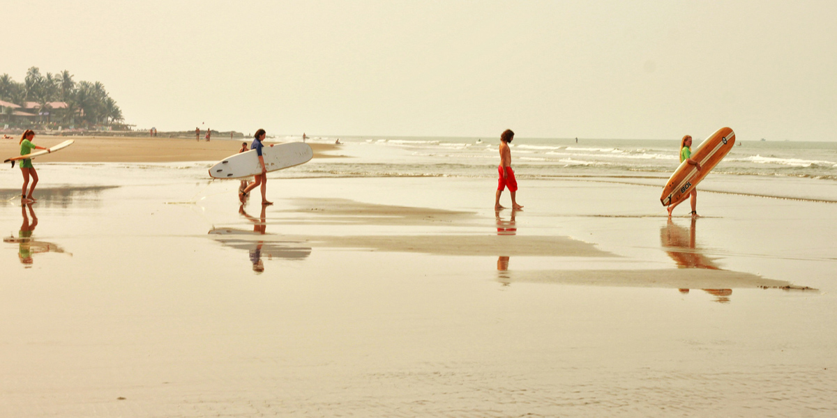 family surfing on the beach in goa
