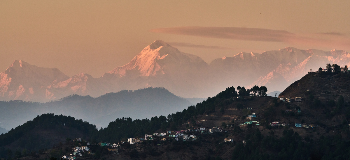 view of himalayasn village with nanda devi on horizon in kumaon