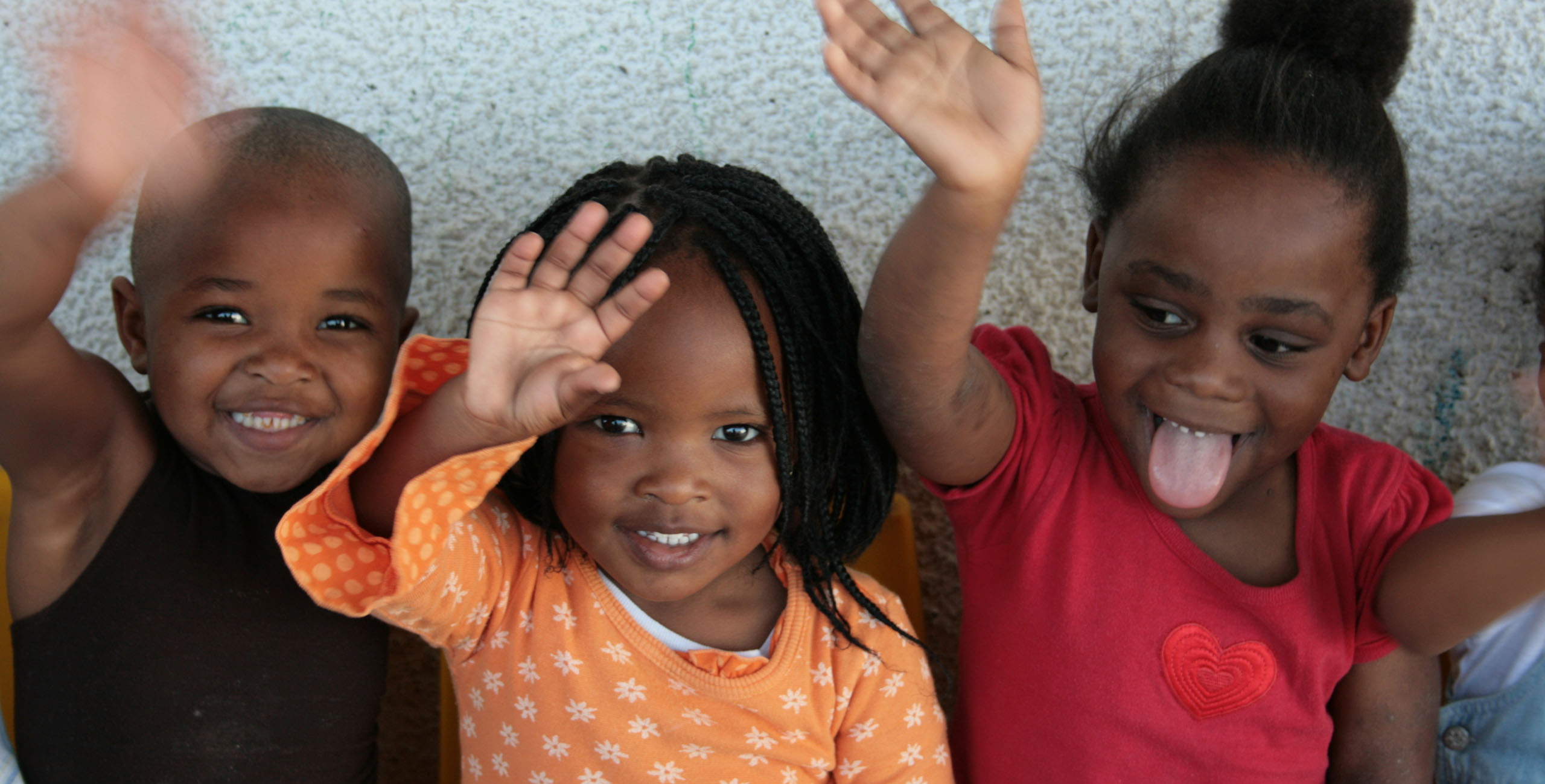 Child waving at camera at uthando's childrens education system in Cape Town, South Africa