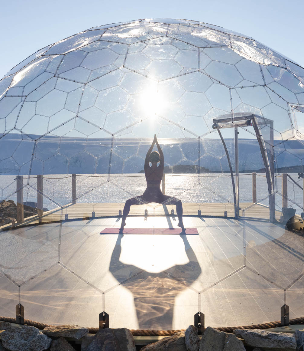 guest doing yoga in glass pod at white desert camp in antarctica