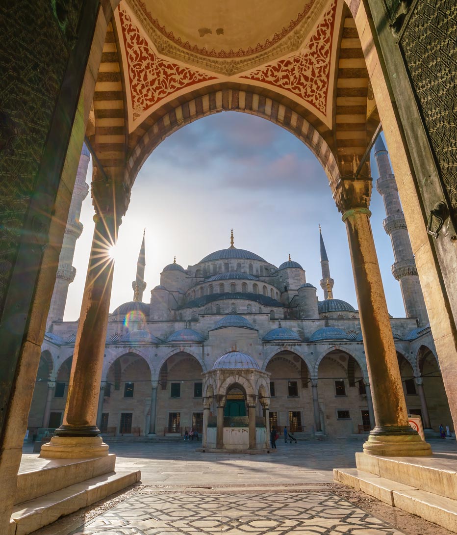 blue mosque in istanbul at sunset seen through a decorated archway