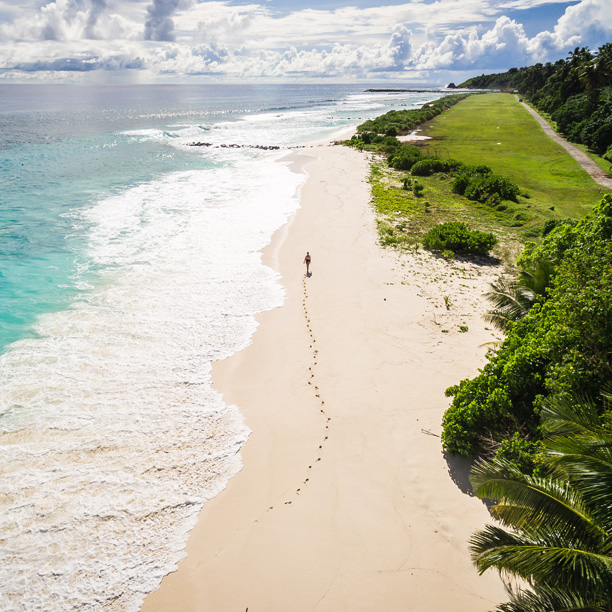 man walking along beach in fregate island